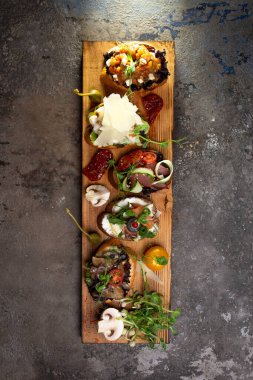 Ahşap bir tahtanın üzerinde değişik aromalı bruschetta..