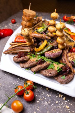 Beyaz bir tabakta farklı et yemekleri..