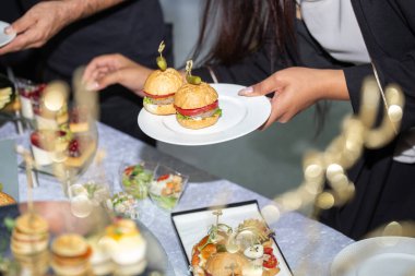 Büfedeki kız hamburgerleri tabakta saklıyor..