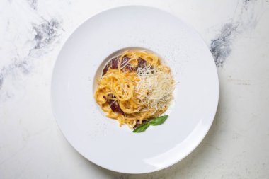 Pastırmalı, kremalı ve peynirli Carbonara makarnası bir restoranda beyaz tabakta..