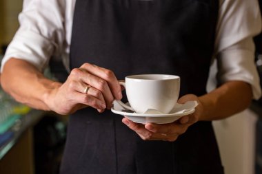 a bartender in a black apron with a cup in his hands. template for design.