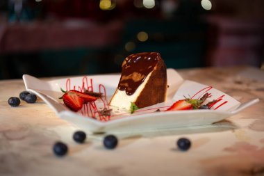 sponge cake with chocolate and berries on a plate in a cafe.