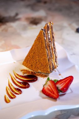 A piece of fresh homemade honey cake with strawberries.
