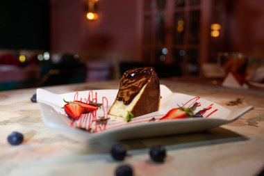 sponge cake with chocolate and berries on a plate in a cafe.
