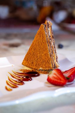 a piece of fresh honey cake with strawberries on a plate.