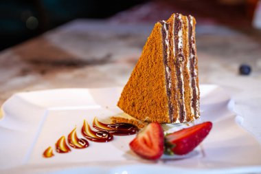 A piece of fresh homemade honey cake with strawberries.