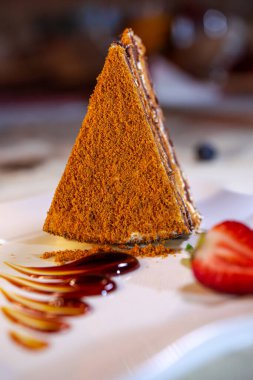 A piece of fresh homemade honey cake with strawberries.