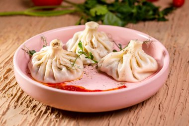 Restoranda pembe tabakta kırmızı soslu üç khinkali..