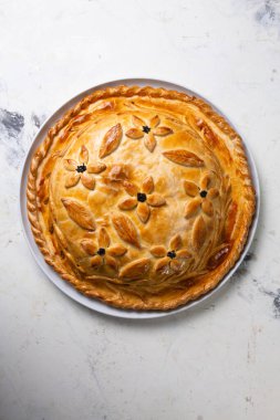Doldurulmuş sıcak ev yapımı tavuklu turtanın üst görüntüsü. Masada pasta var..