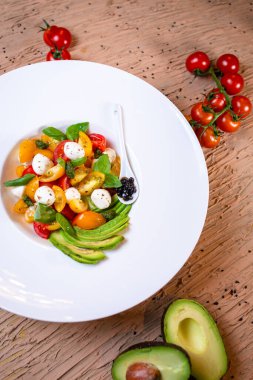 Avacado 'lu salata, mozzarella ve beyaz tabakta domates..