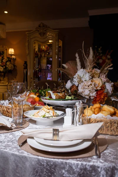テーブルには様々な料理が盛られた白い食器とナプキンが飾られています レストランのお祝いのテーブル — ストック写真