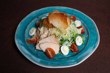 Tavuklu Sezar salatası, taze marul yaprakları ve fırında ekmek..