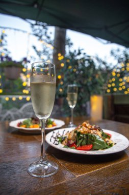 Yazlık kafenin ahşap masasında iki tabak sıcak salata ve bir bardak şarap..