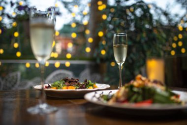 Yazlık kafenin ahşap masasında iki tabak sıcak salata ve bir bardak şarap..