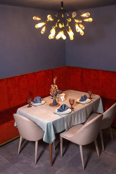 at a set table in a room with blue walls and a red sofa.