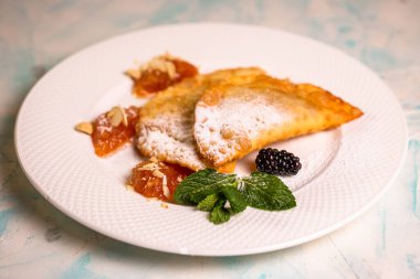 Beyaz bir tabağa şeker serpiştirilmiş tatlı börekler..