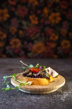 Sığır filetosu ve kavrulmuş mantarlı, taze lahanayla süslenmiş, açık yüzlü sandviçle ahşap bir tabak..