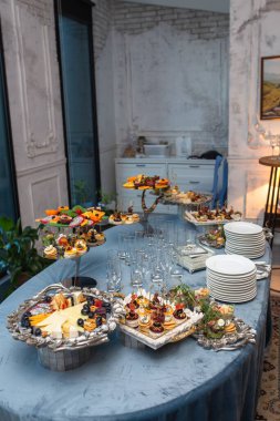 Renkli taze meyve, çeşitli peynirler ve lezzetli aperatiflerle güzel bir yemek masası..