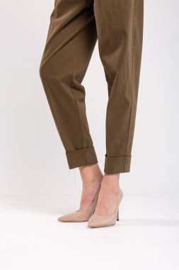 Haki pantolonlu ve bej topuklu ayakkabılı manken. Metin için kopyalama alanı olan beyaz bir arkaplanda izole edilmiş