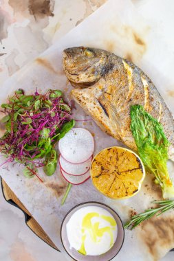 Lezzetli limon ve aromatik otlarla tatlandırılmış ızgara Dorado balığının sunduğu ağız sulandırıcı bir yemek. Beyaz bir tabakta güzelce sunulmuş..