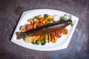 Limon ve maydanozla süslenmiş, çeşitli sebzelerle ızgara balık. Lezzetli deniz ürünleri yemeği..