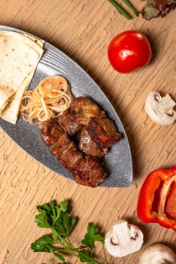 Tahta bir masada sebzeli ve otlu sulu et kebabı. Yukarıdan görünüm.