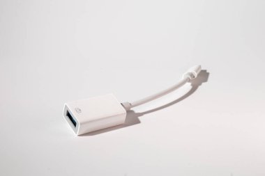 Bileşik maddeden yapılmış beyaz bir ışık kablosu cam bir masanın üzerinde duruyor ve şeffaf ve modern bir görünüm yaratıyor.