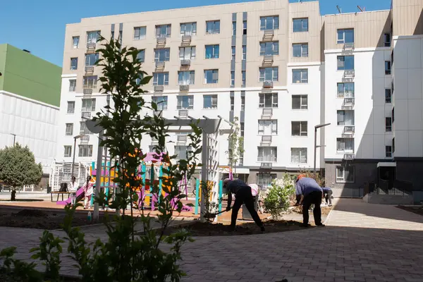 Bahçesi olan modern apartman binaları. Çağdaş tasarım, büyük pencereler, balkonlar. Salıncaklı, kaydırmalı, tırmanmalı oyun alanı.