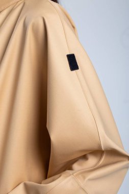 Şehir merkezinde beyaz duvar arkasında fotokopi alanı olan bej renkli yağmurluk giyen zarif bir kadın model. Şık ve şık görünüm..