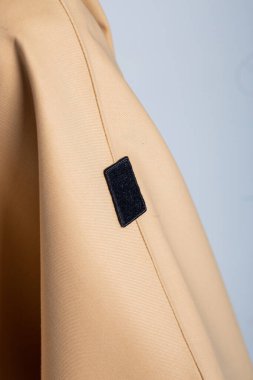 Şehir merkezinde beyaz duvar arkasında fotokopi alanı olan bej renkli yağmurluk giyen zarif bir kadın model. Şık ve şık görünüm..