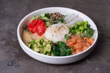 Somon, avokado, salatalık, lahana ve pirinçle bembeyaz tabakta bir veda kasesinin üst görüntüsü..