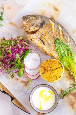 Lezzetli limon ve aromatik otlarla tatlandırılmış ızgara Dorado balığının sunduğu ağız sulandırıcı bir yemek. Beyaz bir tabakta güzelce sunulmuş..