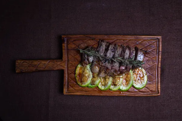 stock image Tender beef steak with grilled zucchini on a wooden board, a delicious and healthy meal option for food enthusiasts.