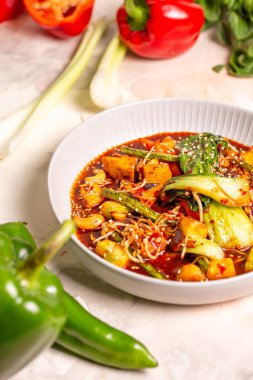 Sebzeli kırmızı köri, beyaz arkaplanda tofu. Hindistan cevizi sütü, kırmızı köri ezmesi, susam tohumuyla süslenmiş..