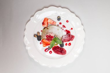 Beyaz tabakta krep, meyve ve böğürtlenli lezzetli ve sağlıklı bir kahvaltı. İzole edilmiş. Sağlıklı yeme kavramı.