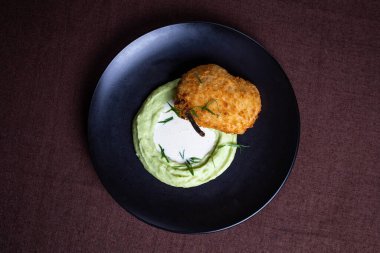 Kiev usulü kızarmış tavuk pirzolası ve siyah tabakta patates püresi..