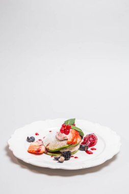 Taze çilek, yabanmersini, yaban mersini ve beyaz tabakta kremalı böğürtlen. Sağlıklı kahvaltı ve diyet konsepti.