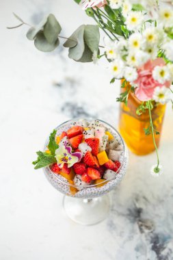 Çilekli Chia tohumu pudingi, mango, mermer masada cam içinde ejderha meyvesi. Sağlıklı vejetaryen kahvaltısı veya atıştırmalık.