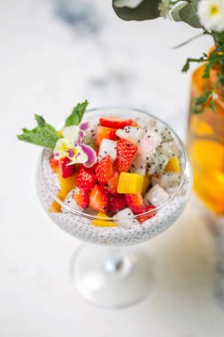 Çilekli Chia tohumu pudingi, mango, mermer masada cam içinde ejderha meyvesi. Sağlıklı vejetaryen kahvaltısı veya atıştırmalık.