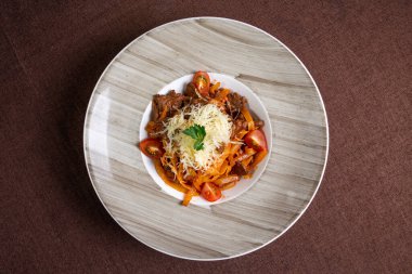 Makarnalı, domatesli ve peynirli leziz bir et yahnisi tabağının üst görüntüsü, öğle ya da akşam yemeği için mükemmel..