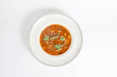 Geleneksel Gürcistan fasulye çorbası Lobio, beyaz arka planda seramik tabakta bitkiler. en üstteki görünüm.