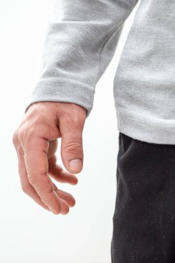 Beyaz bir duvara karşı gri bir kazak giymiş bir adamın yakın çekimi. Kumaş dokusunu ve doğal pozu gösteren detaylı fotoğraf. Moda ve reklam modelleri için mükemmel..