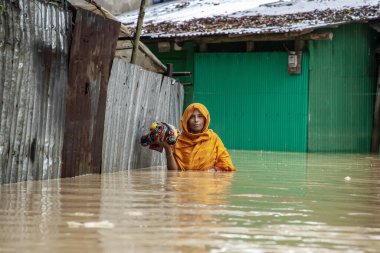 9 Ağustos 2023 'te Güney Chittagong, Bangladeş' ten Satkania Upazila 'da göğüs ve bel seviyesindeki suyla dolu yol boyunca yayalar, kamyonlar ve bisikletler yürüyor..