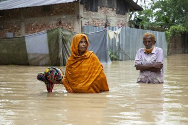 9 Ağustos 2023 'te Güney Chittagong, Bangladeş' ten Satkania Upazila 'da göğüs ve bel seviyesindeki suyla dolu yol boyunca yayalar, kamyonlar ve bisikletler yürüyor..