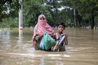9 Ağustos 2023 'te Güney Chittagong, Bangladeş' ten Satkania Upazila 'da göğüs ve bel seviyesindeki suyla dolu yol boyunca yayalar, kamyonlar ve bisikletler yürüyor..