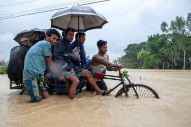 9 Ağustos 2023 'te Güney Chittagong, Bangladeş' ten Satkania Upazila 'da göğüs ve bel seviyesindeki suyla dolu yol boyunca yayalar, kamyonlar ve bisikletler yürüyor..
