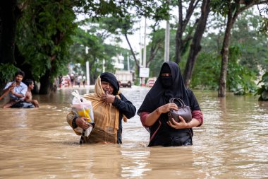 9 Ağustos 2023 'te Güney Chittagong, Bangladeş' ten Satkania Upazila 'da göğüs ve bel seviyesindeki suyla dolu yol boyunca yayalar, kamyonlar ve bisikletler yürüyor..
