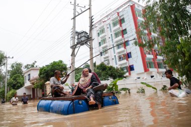 9 Ağustos 2023 'te Güney Chittagong, Bangladeş' ten Satkania Upazila 'da göğüs ve bel seviyesindeki suyla dolu yol boyunca yayalar, kamyonlar ve bisikletler yürüyor..