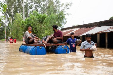 9 Ağustos 2023 'te Güney Chittagong, Bangladeş' ten Satkania Upazila 'da göğüs ve bel seviyesindeki suyla dolu yol boyunca yayalar, kamyonlar ve bisikletler yürüyor..