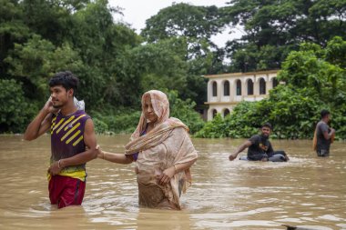 9 Ağustos 2023 'te Güney Chittagong, Bangladeş' ten Satkania Upazila 'da göğüs ve bel seviyesindeki suyla dolu yol boyunca yayalar, kamyonlar ve bisikletler yürüyor..